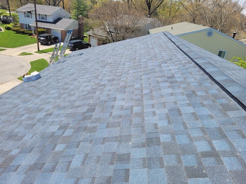 Close view of new light grey shingles on a roof with a ladder at the edge