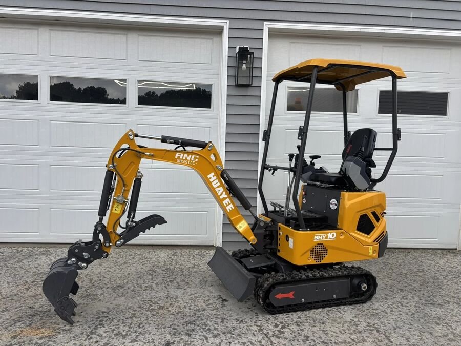 Orange Huayee SHY10 mini excavator with canopy parked in front of white garage doors