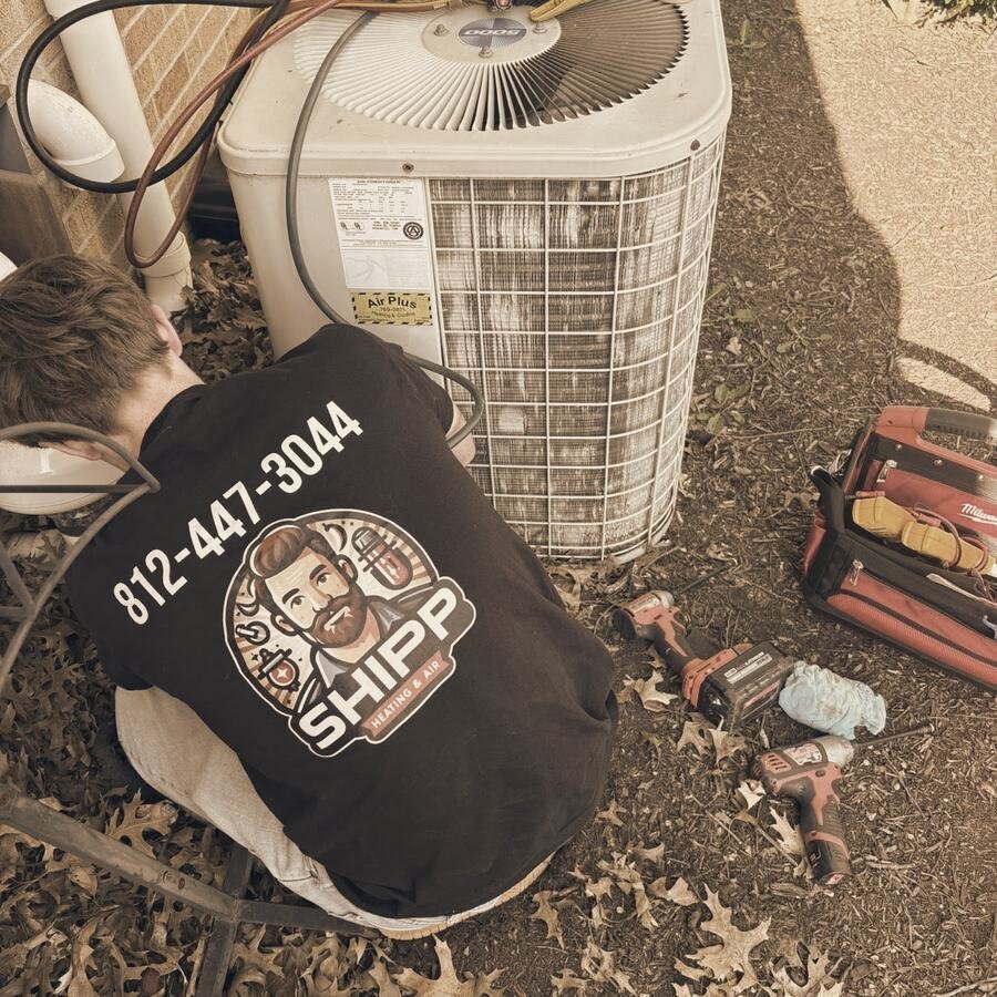 Shipp's tech working on an outdoor AC condenser, the SHIPP logo and 812-447-3044 on the back of his shirt