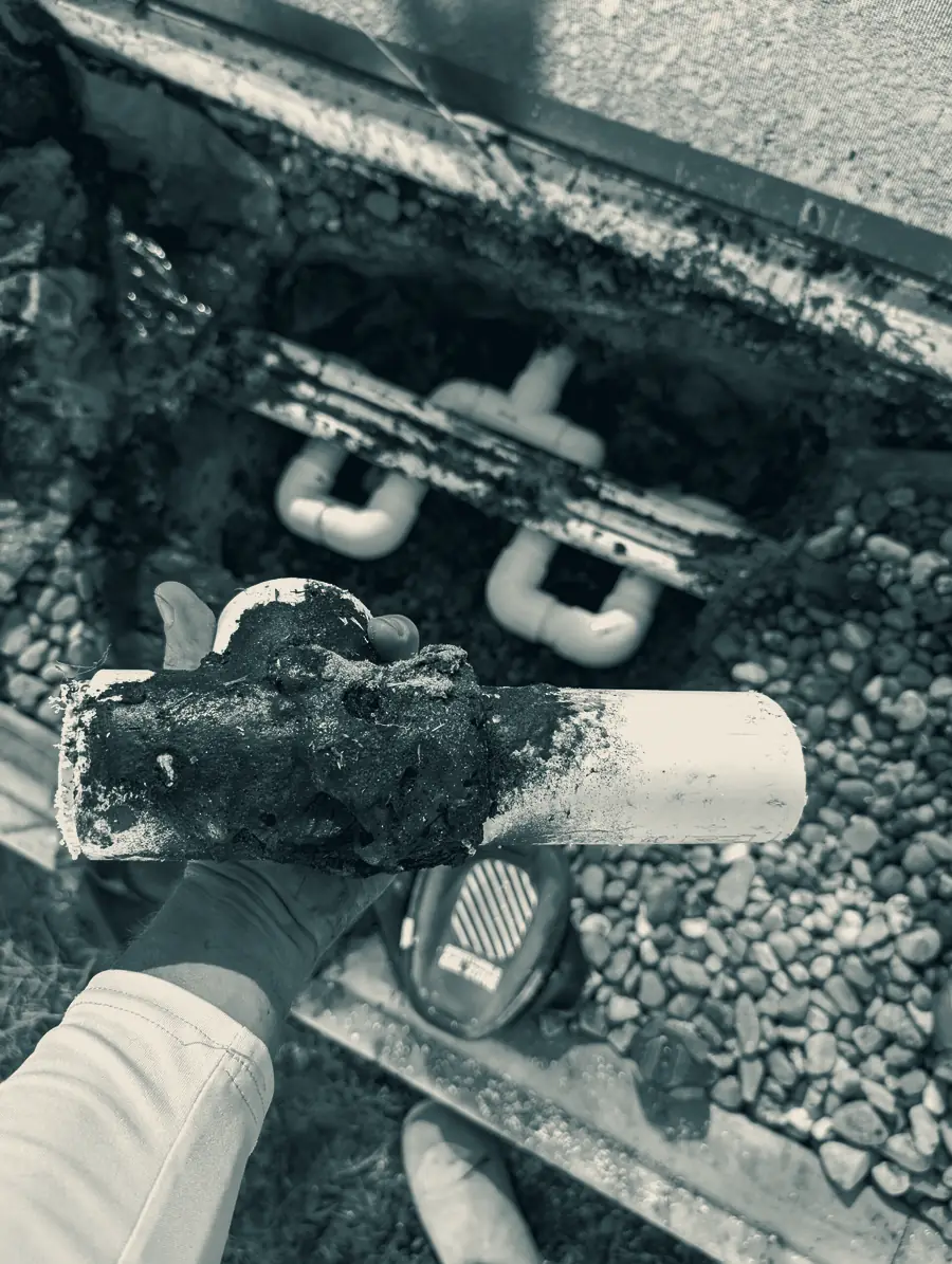 A Splash technician holding the corroded section of pool plumbing pipe excavated from beneath a deck